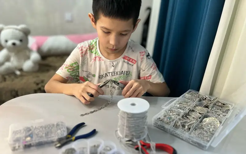 школьник вместе с мамой изготавливает казахские украшения в Семее  