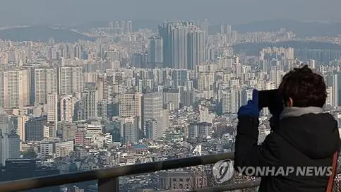 A woman takes a picture of skyscrapers from Namsan Observatory in Seoul
