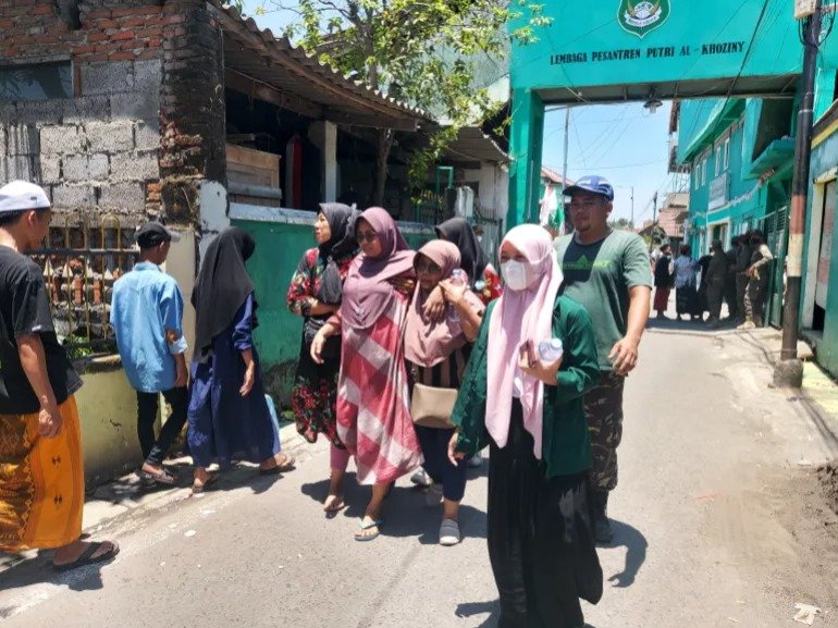 Distressed relatives walk to the forensic tent at the site of the collapsed school in Sidoarjo