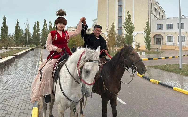 Молодая пара из Китая верхом на лошадях приближается к Астане