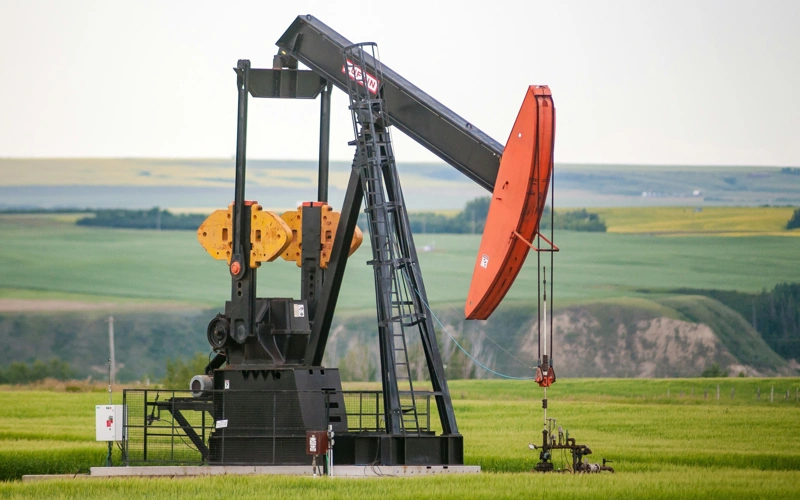 A pump jack in the middle of a Canola Field on the banks of the Red Deer River valley, Canada.