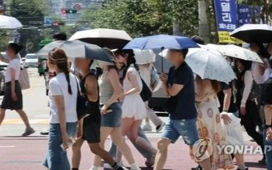 People walk with parasols on a street in eastern Seoul on Aug. 7, 2026, amid an extreme heat wave